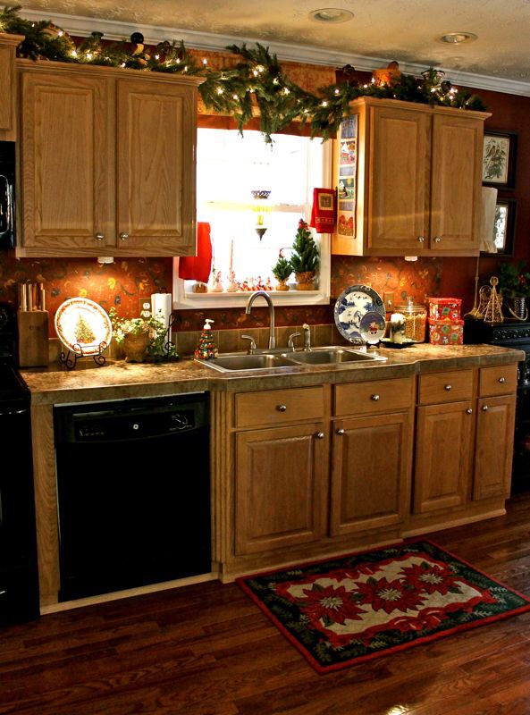Green garland with pine cones and red berries draped over kitchen cabinets