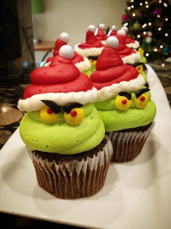 Grinch-themed Christmas treats green cupcakes with grumpy faces, roast beast cookies with pink hearts and a Grinch head punch bowl with gummy worms