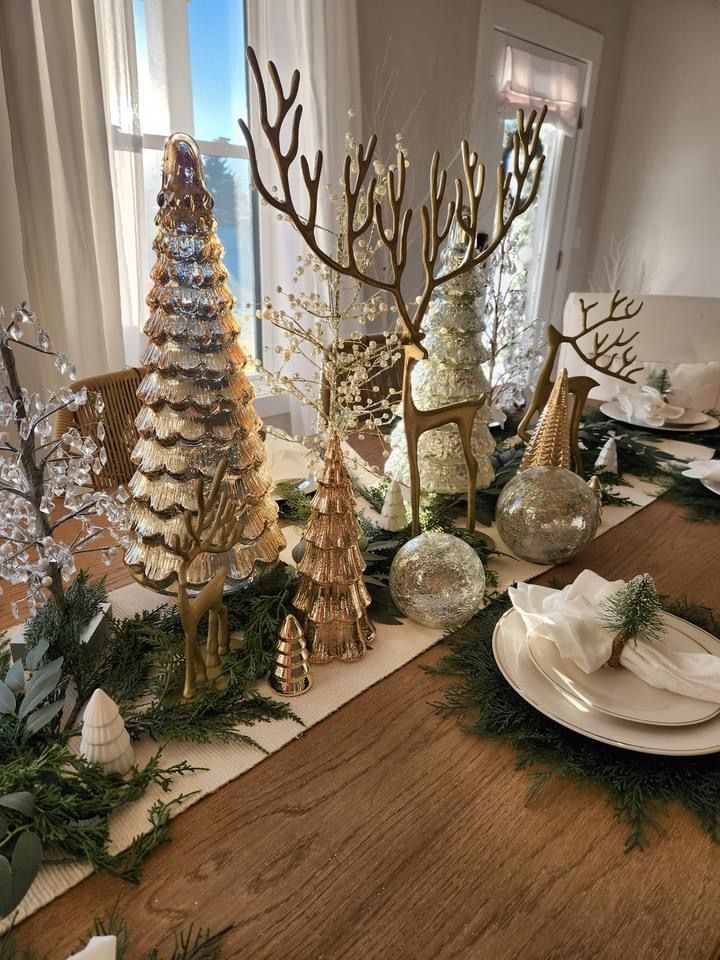 rustic wooden tray filled with pinecones, candles, ornaments, and greenery placed as a centerpiece on a kitchen table.
