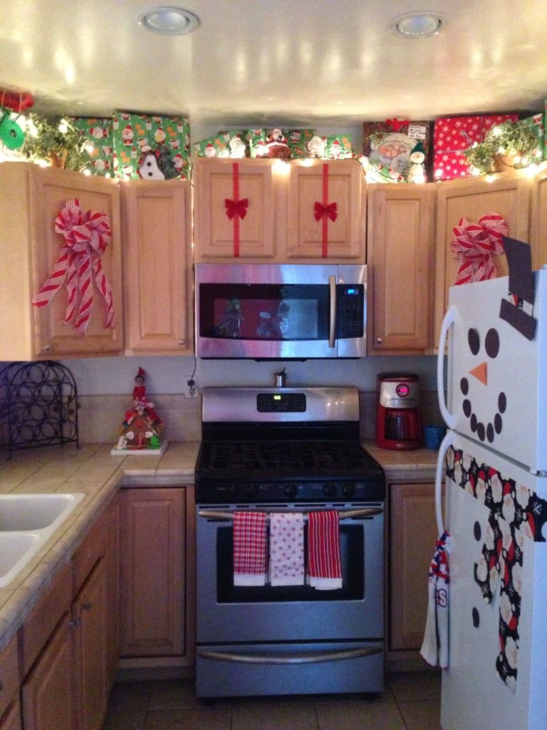 stainless steel kitchen refrigerator decorated with a large red bow and a Santa hat ornament on the handle