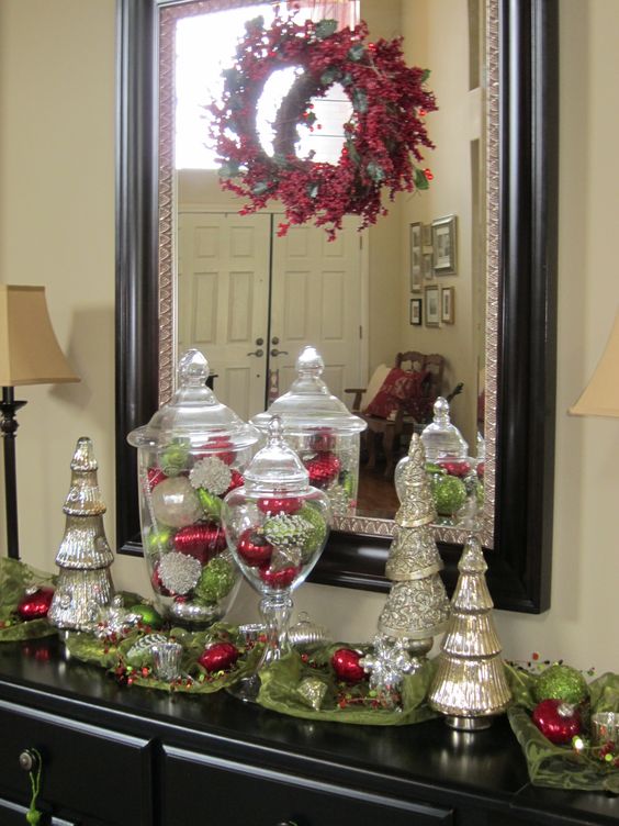 variety of handmade Christmas ornaments, including painted pinecones, crocheted snowflakes, and personalized ornaments, hanging from a kitchen window